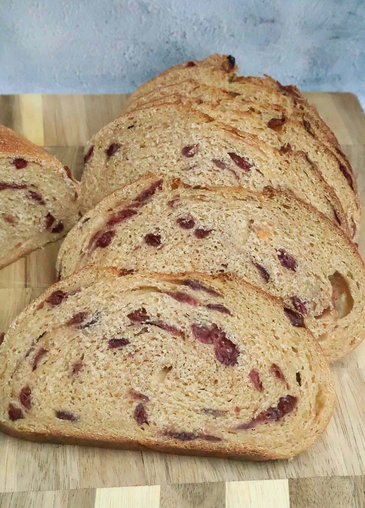 Slices of cranberry sourdough bread on a wooden cutting board.