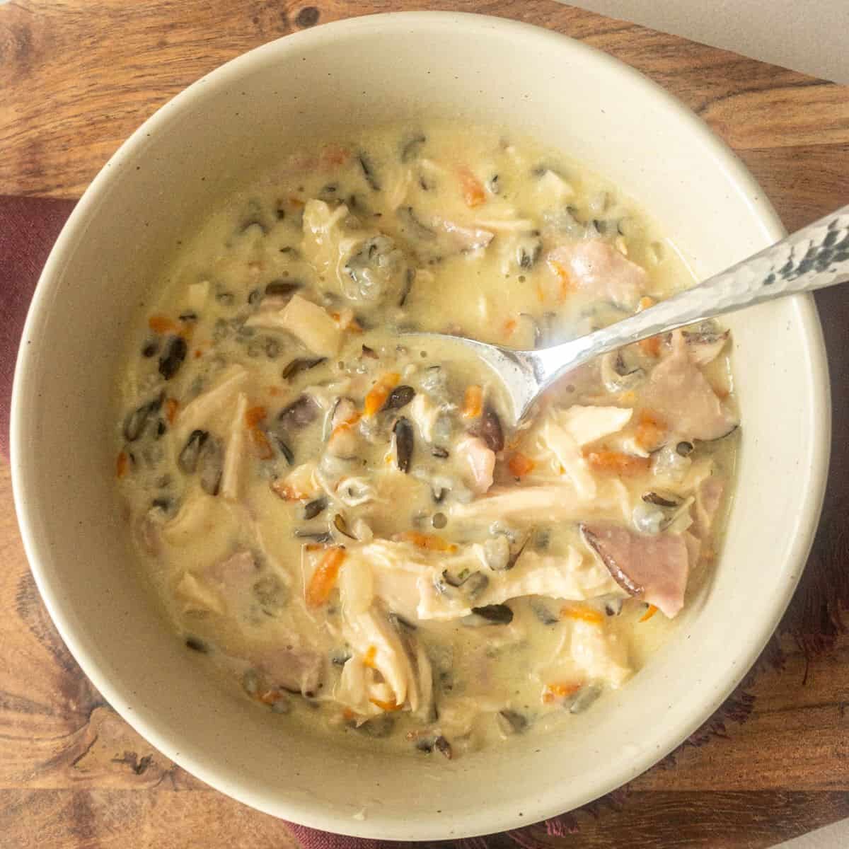 bowl of wild rice soup with spoon on wooden background