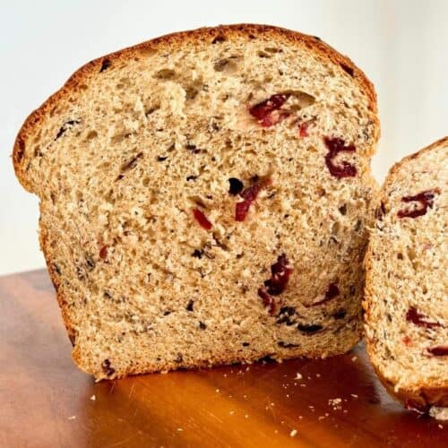loaf of cranberry wild rice bread sliced open on cutting board