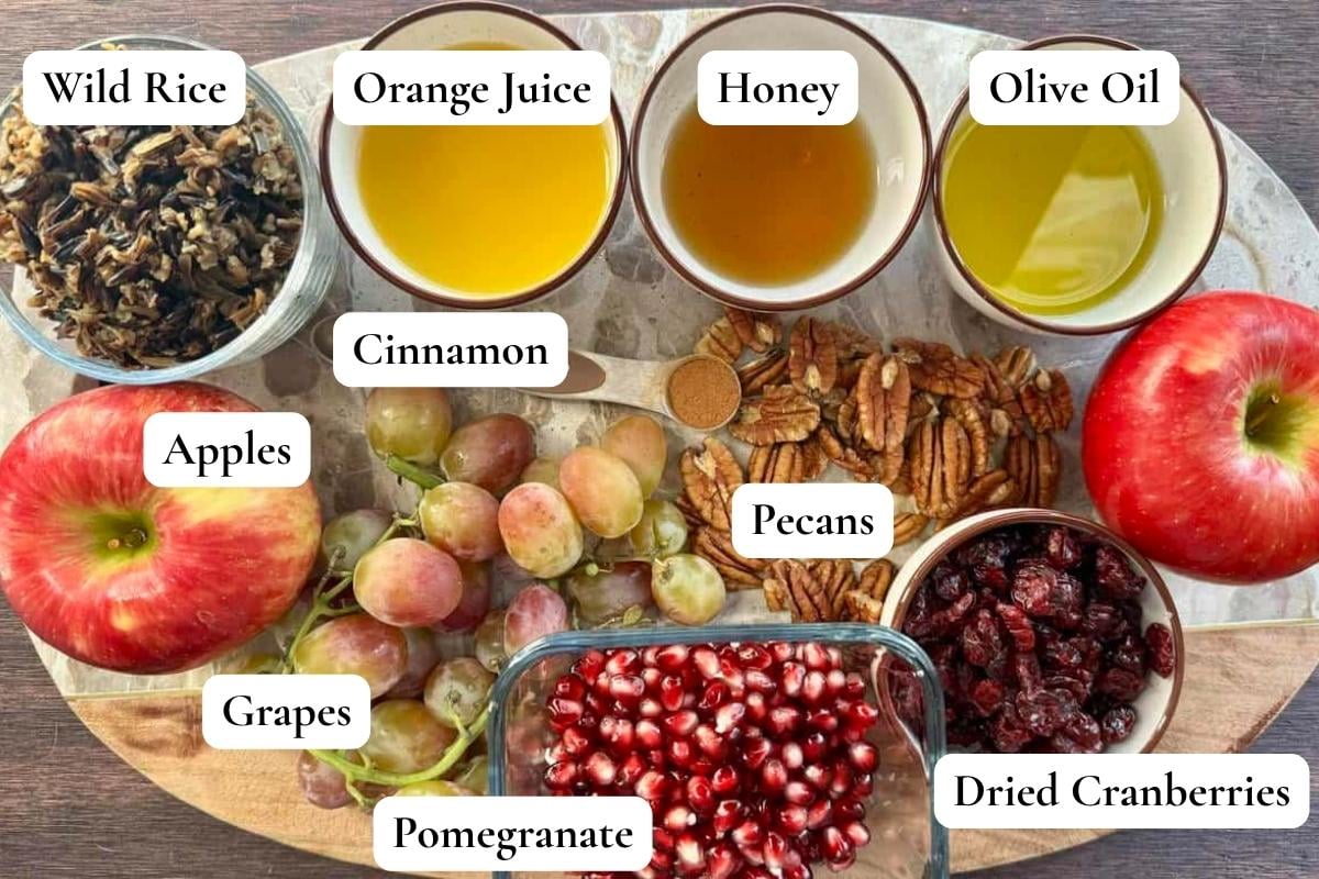Assortment of fruit salad ingredients in small white bowls and sitting on marble platter.