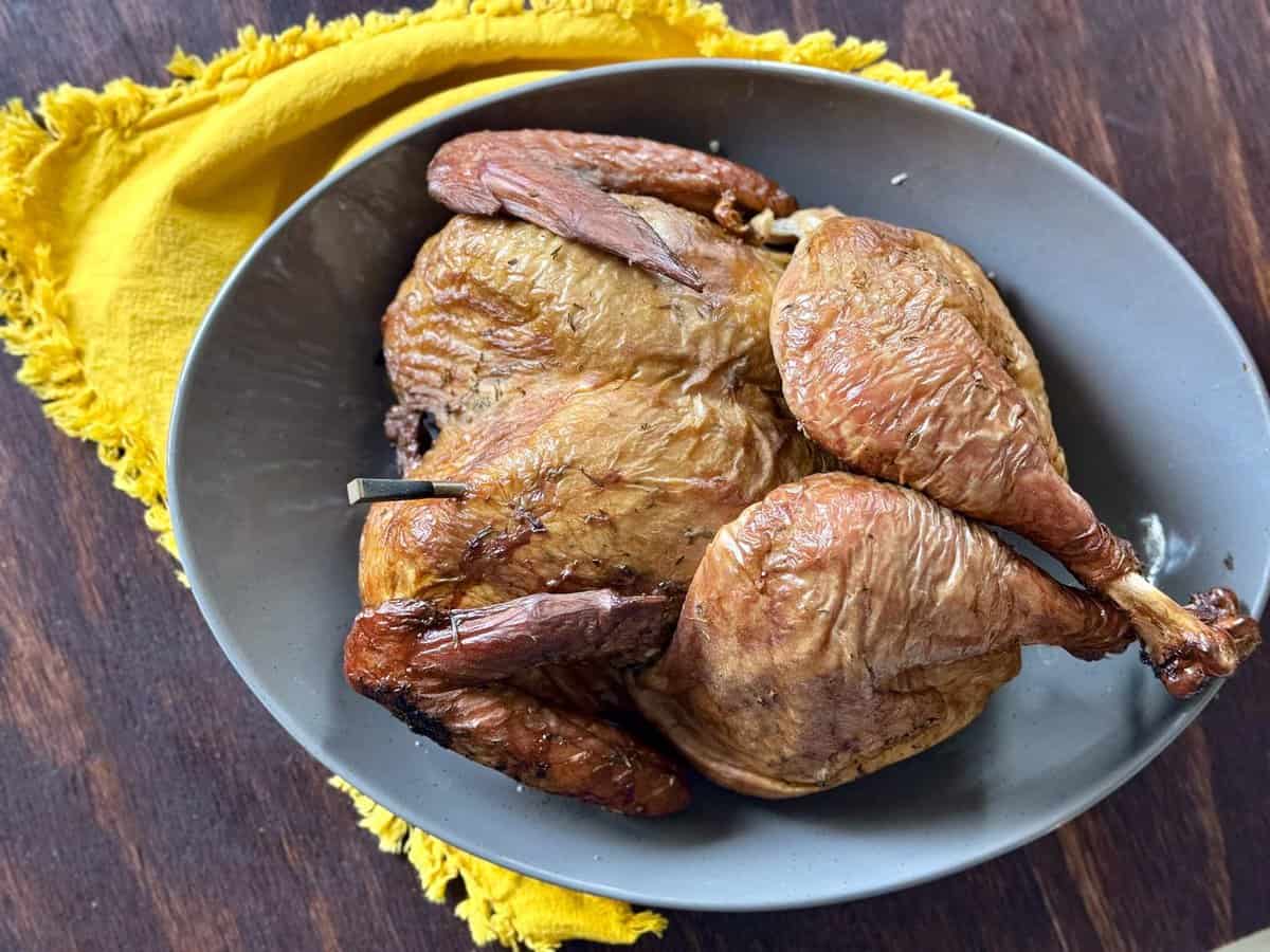 smoked whole turkey on gray plate with yellow napkin