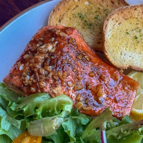 Close up of traeger grilled salmon recipe filet with salad and garlic toast, lemon slices