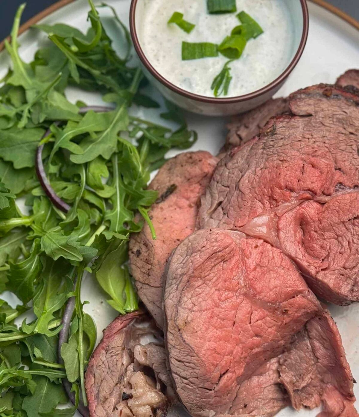plate of ribeye roast on traeger with salad and sauce