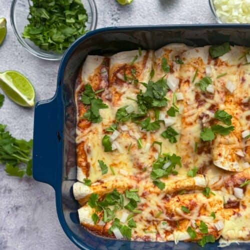 close up of of birria enchiladas with toppings and lime wedges