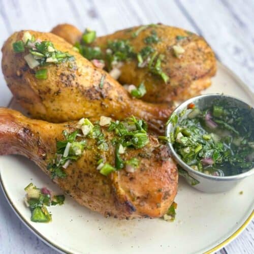 smoked traeger chicken legs with chimichurri drizzle on white plate