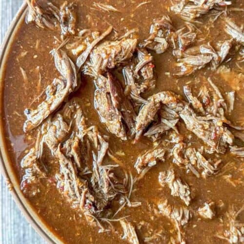 shredded beef birria in sauce in a bowl.