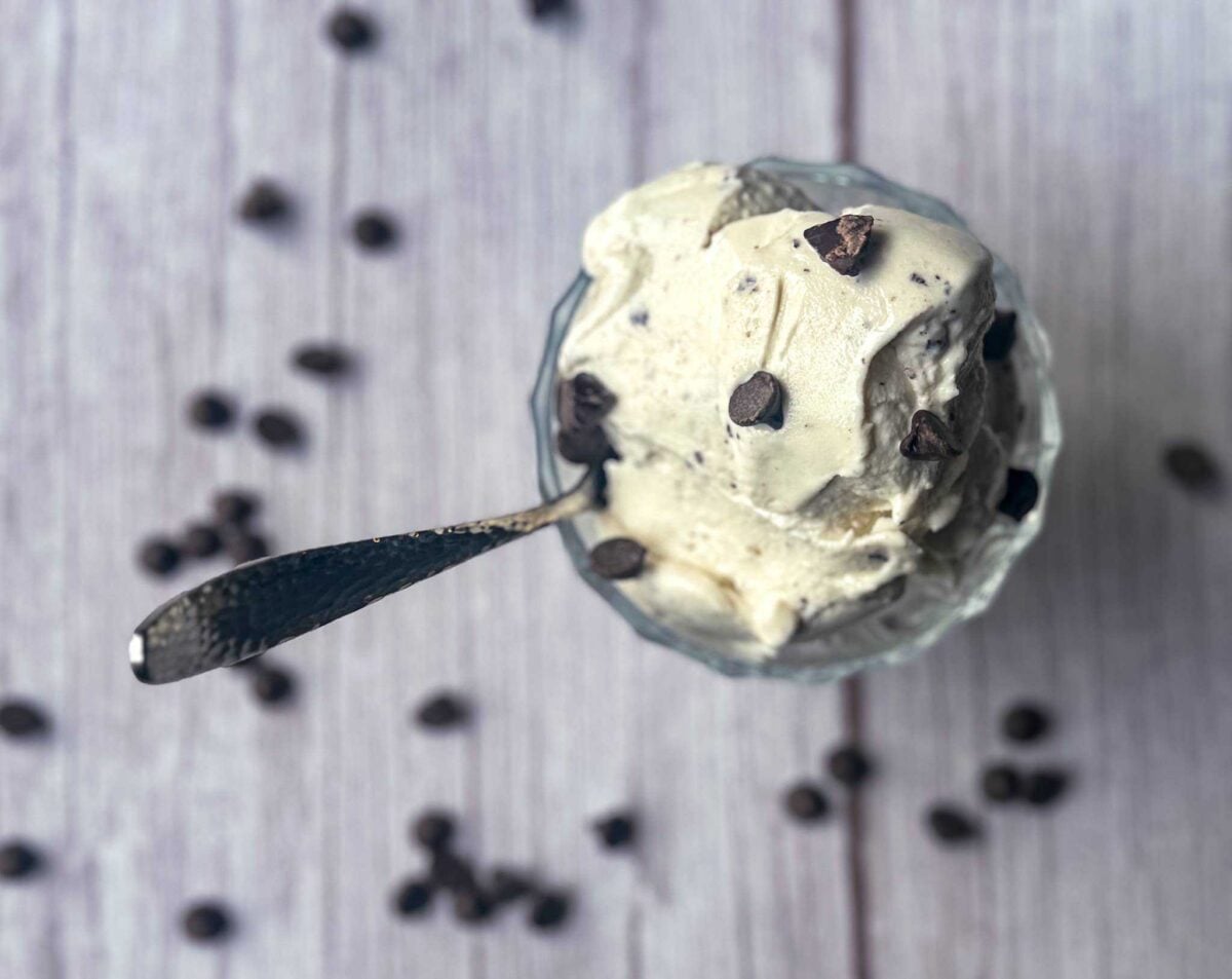 This is a dish of mint chocolate chip protein ice cream garnished with extra chocolate chips on a gray backdrop.