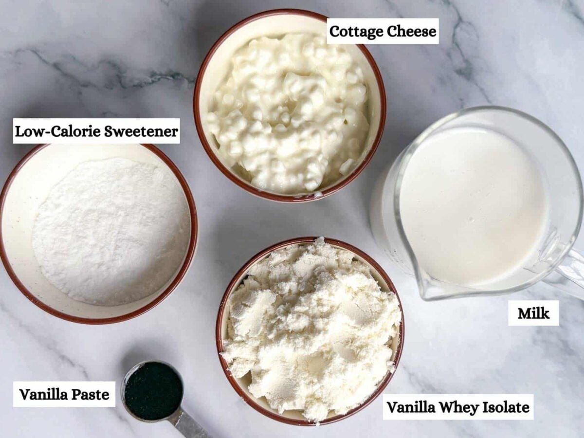 This is all of the ingredients for the vanilla Ninja Creami base recipe in little bowls on a marble background.