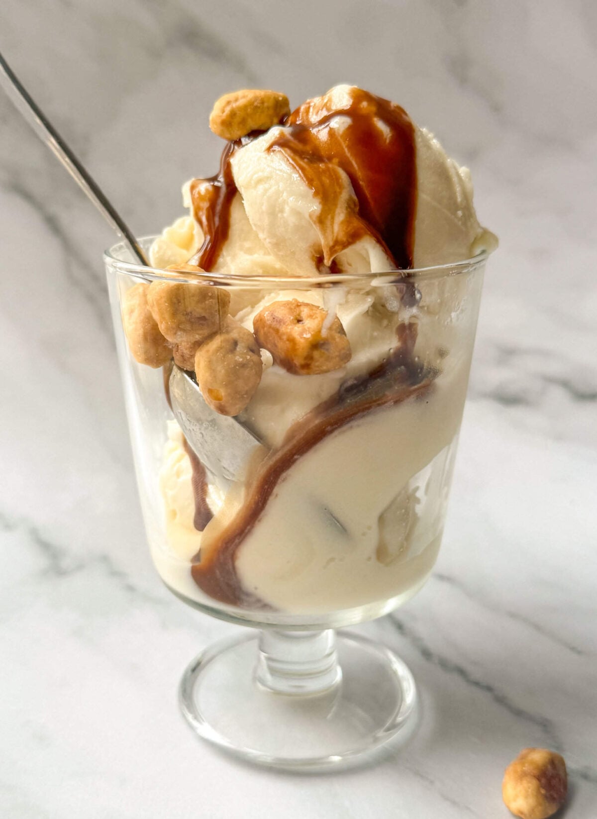 This is a vanilla Ninja Cream base recipe ice cream sundae in a glass dish with chocolate sauce and peanuts.