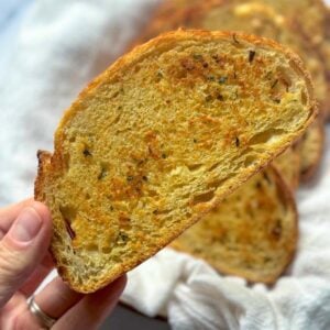 holding a slice of toasted sourdough garlic toast