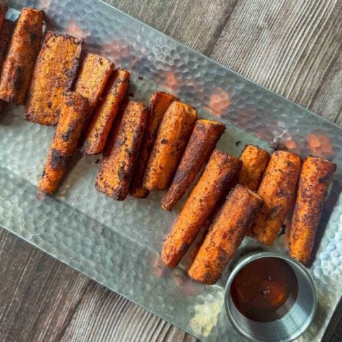 Platter of smoked carrot pieces with cup of hot honey.