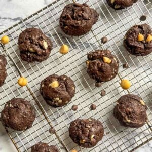 A cooling rack of cookies garnished with nuts and chocolate chips.