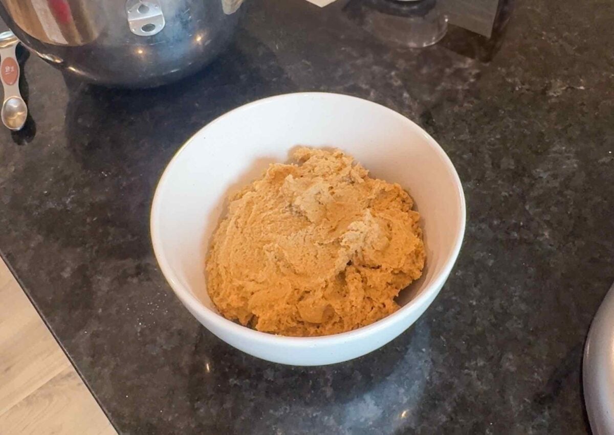 A white bowl of finished dough ready for the fridge.