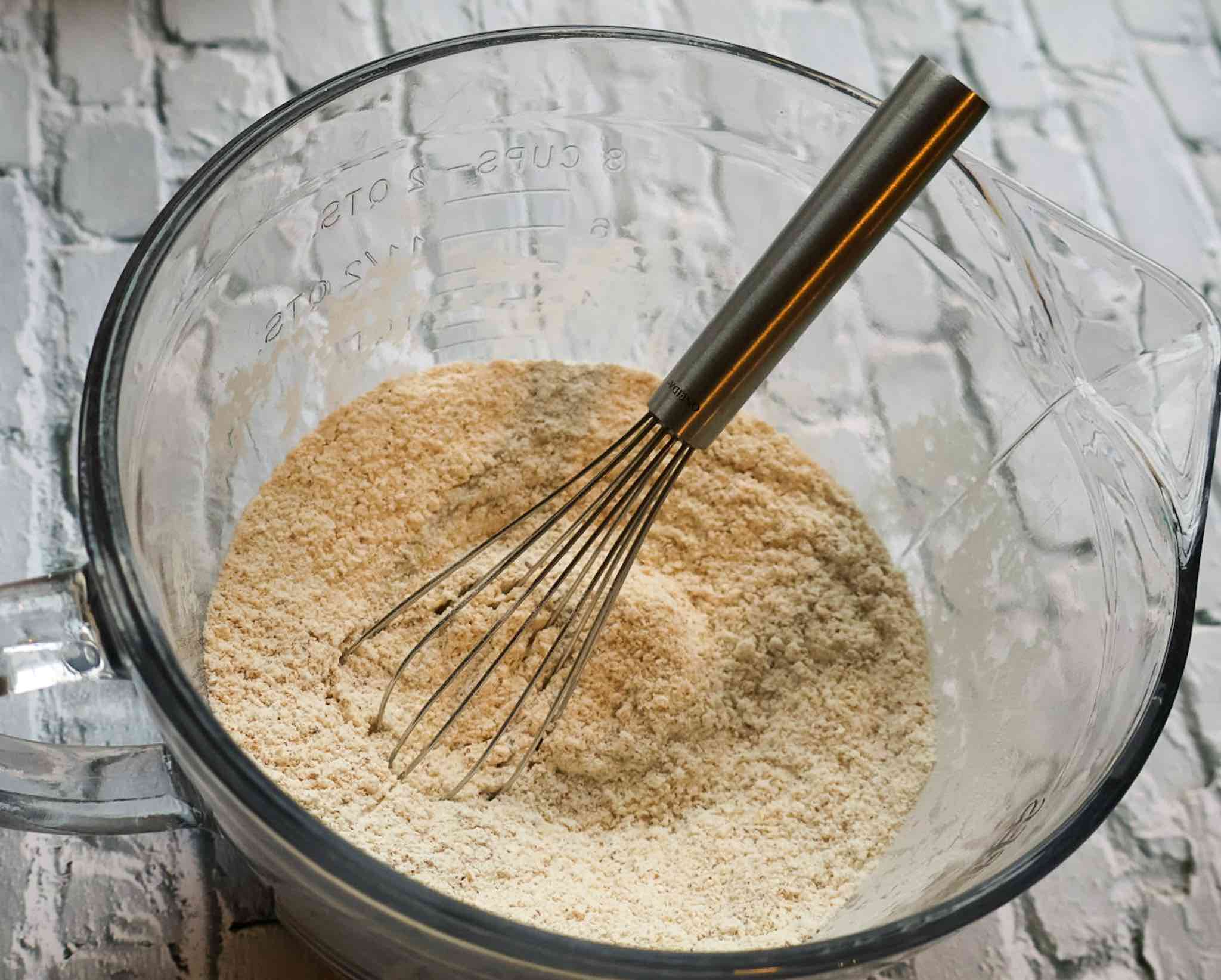 a glass bowl of homemade kodiak pancake mix with whisk.