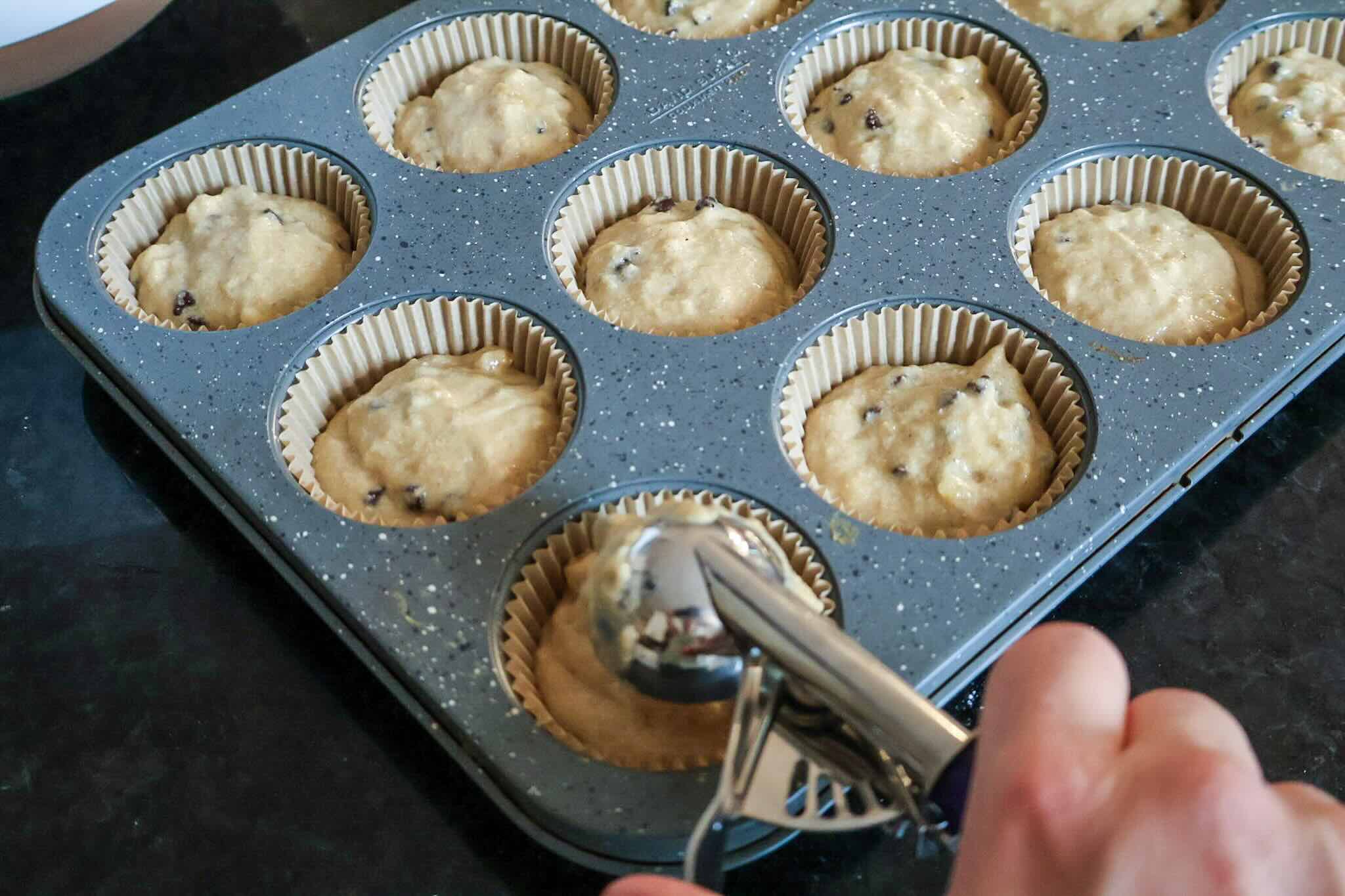 Scooping muffin batter into the muffin pan.