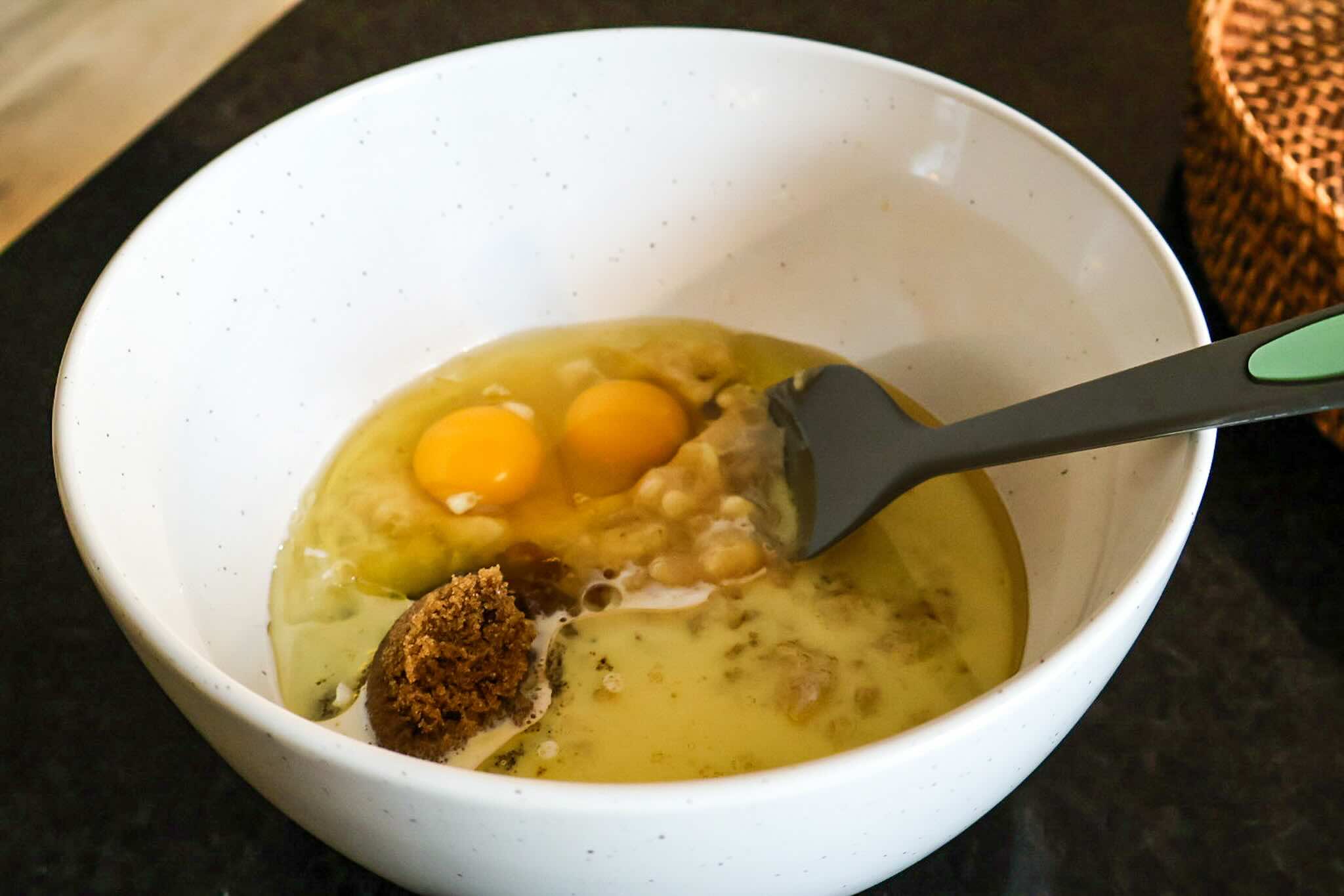 White mixing bowl filled with wet recipe ingredients.