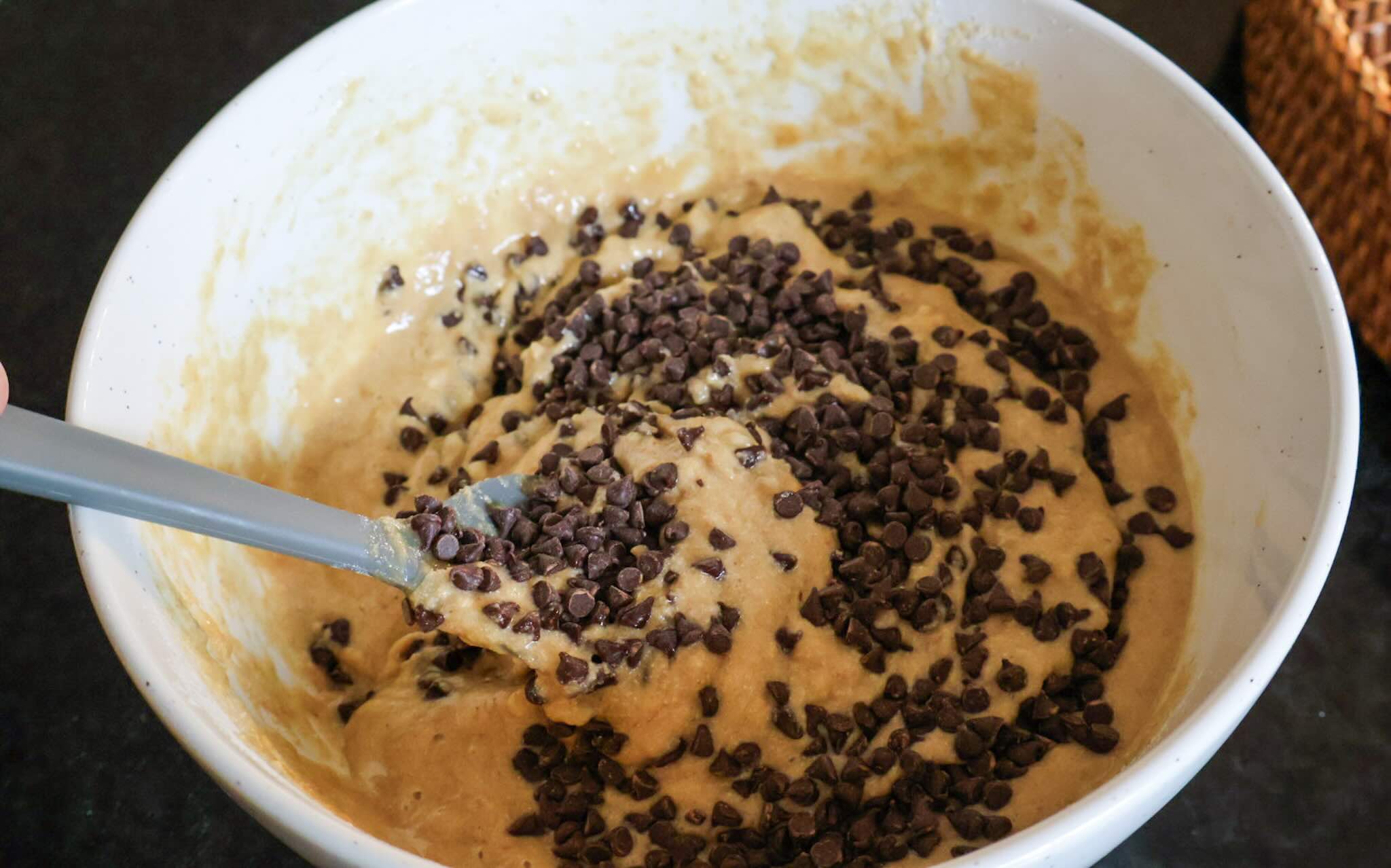 Folding chocolate chips into the batter with a rubber spatula.