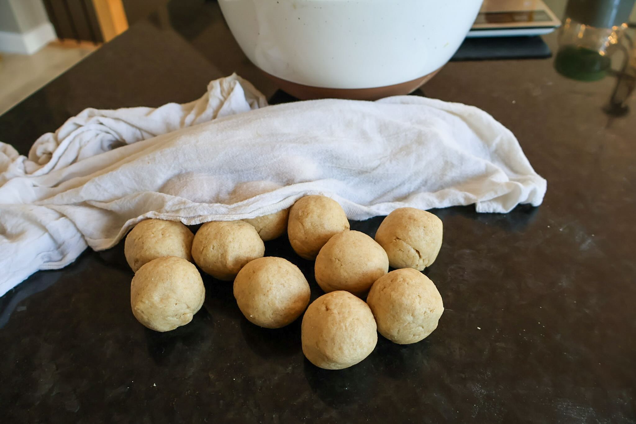 A bunch of dough balls resting under damp towel.