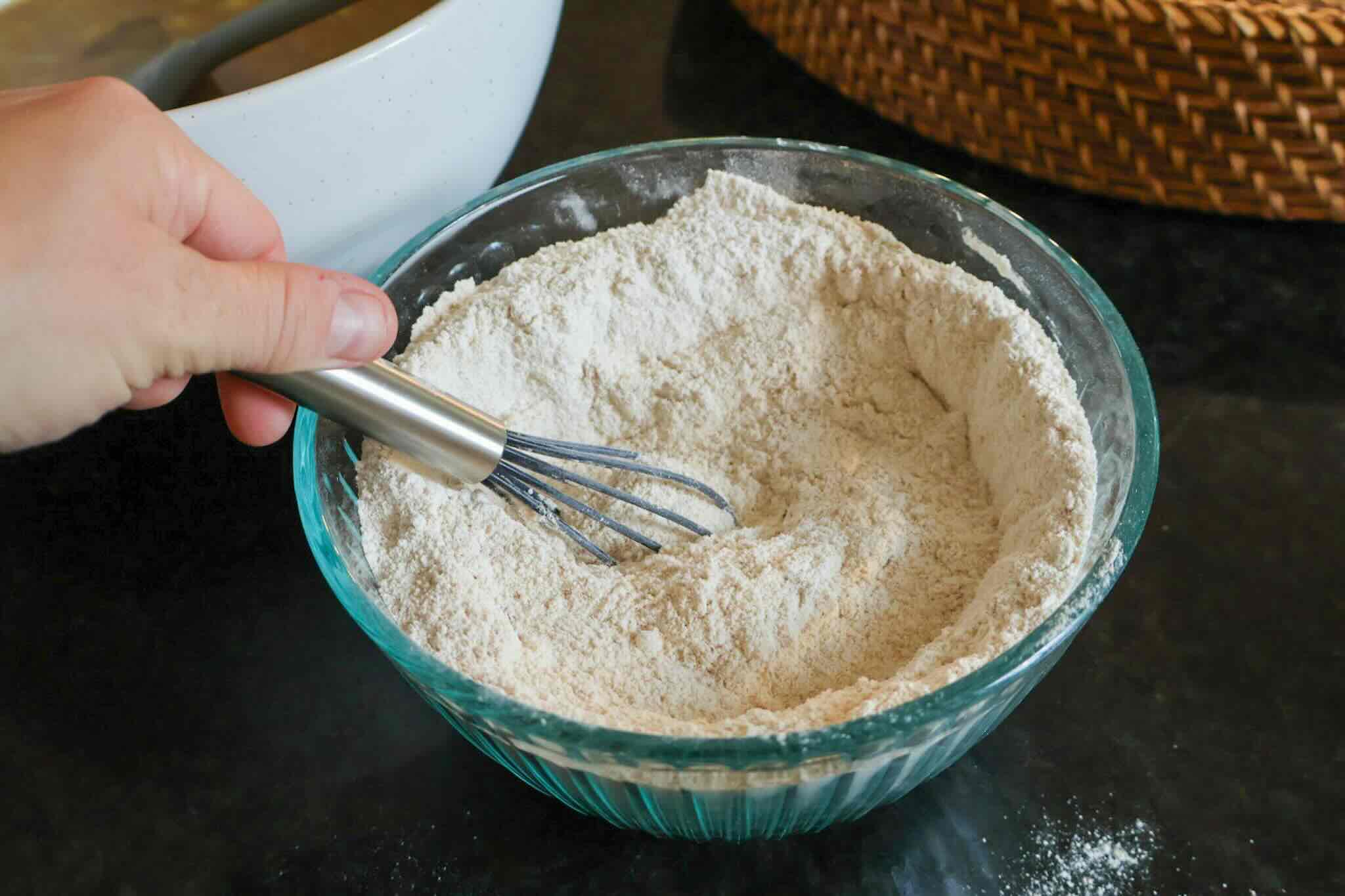 Bowl of flour with small whisk.