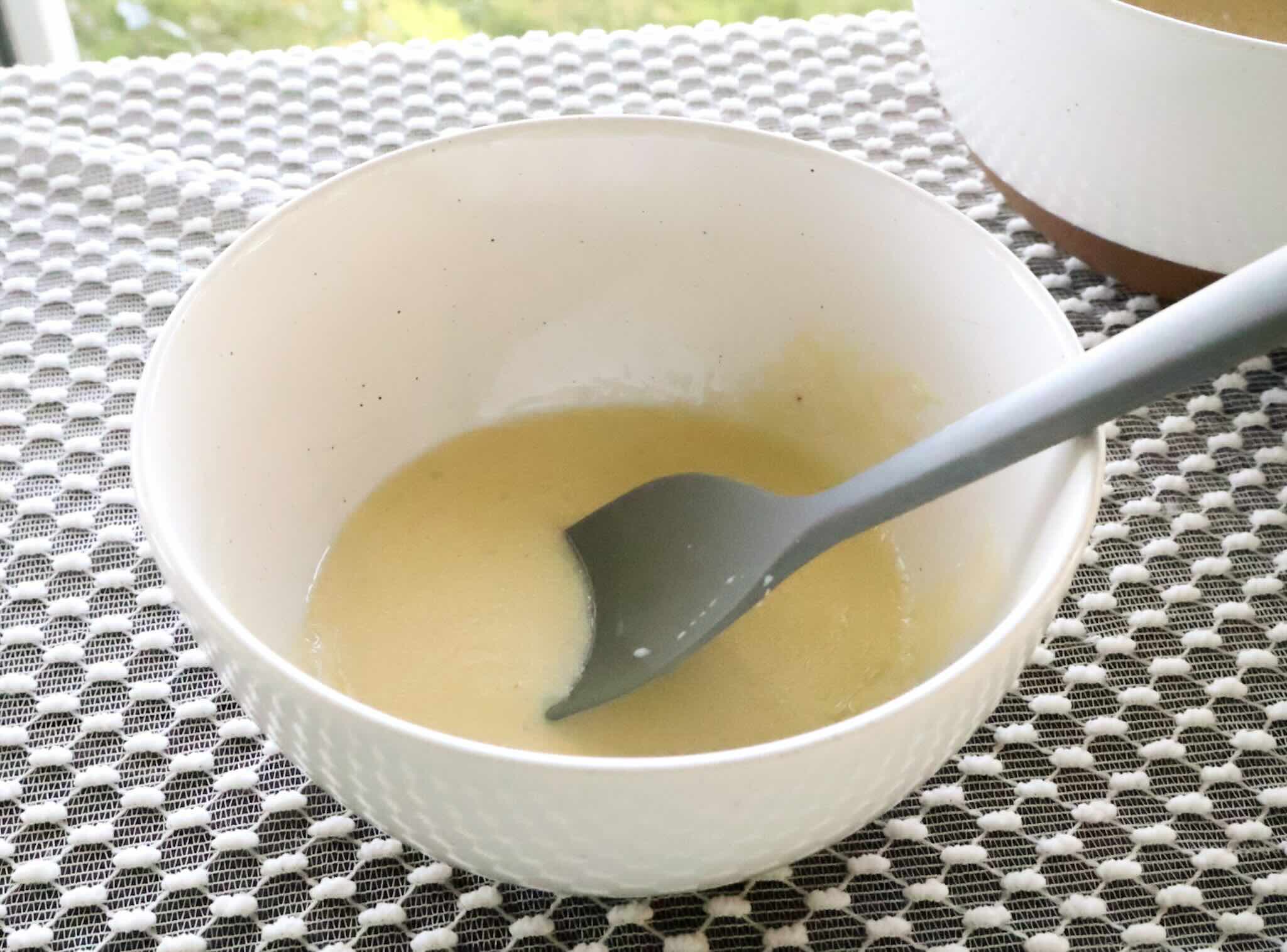 White mixing bowl of wet ingredients on table with lace cloth.