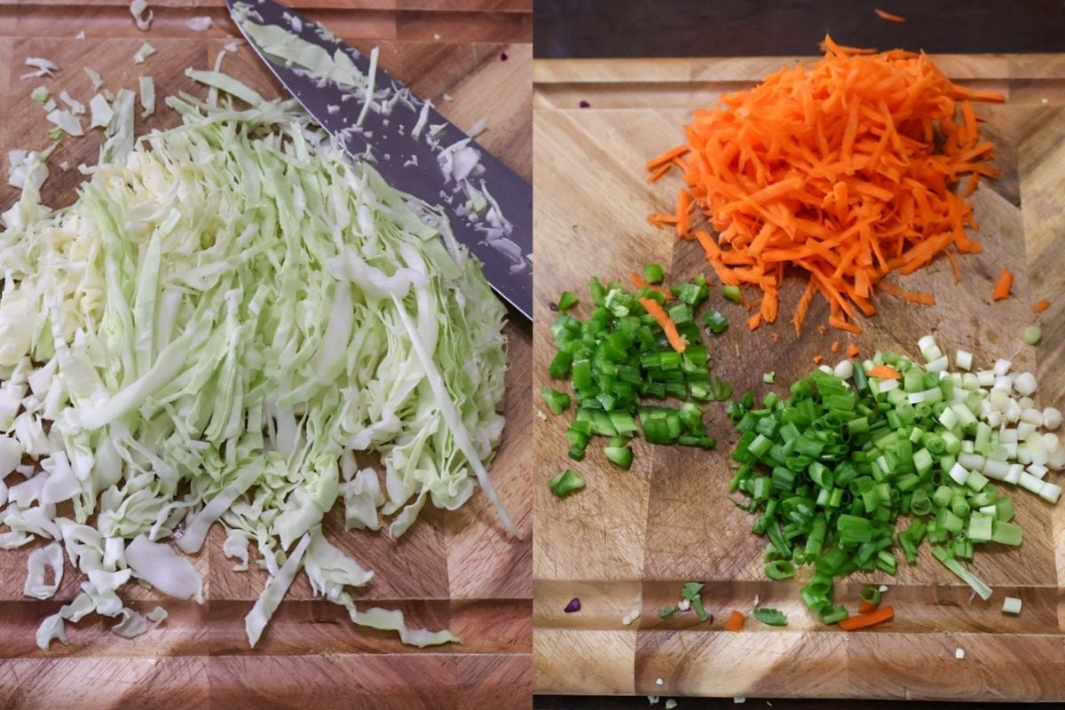 Finely sliced cabbage, chopped carrot, onion, and jalapeño on wooden chopping board.