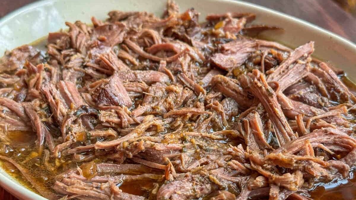 side view of shredded sirloin tip roast with juices on serving platter
